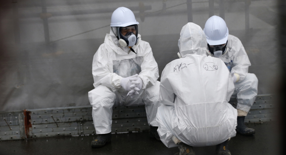 Workers wearing radiation protective gear rest near TEPCO’s tsunami-crippled Fukushima Daiichi nuclear power plant.