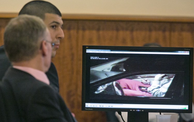 Aaron Hernandez, rear, and his attorney Charles Rankin watch surveillance video of Hernandez handling cell phones during his murder trial in Fall River, Mass., Tuesday.