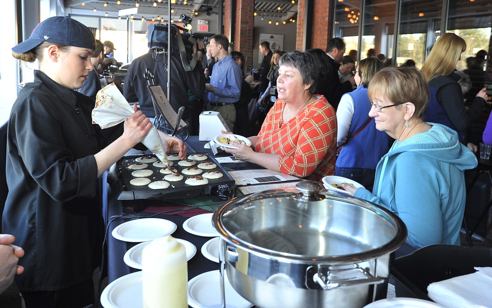 SOUTH PORTLAND, ME - FEBRUARY 27: Mary Gresik of Scarborough, center, and Phyllis Sargent of OOB await their serving of a cinnamon bun pancake with cream cheese frosting from head chef Nicole Steinmark, left, of Bintliff's American Cafe at the Incredible Breakfast Cook-Off held at Sea Dog Brewing Company in South Portland. (Photo by Gordon Chibroski/Staff Photographer)