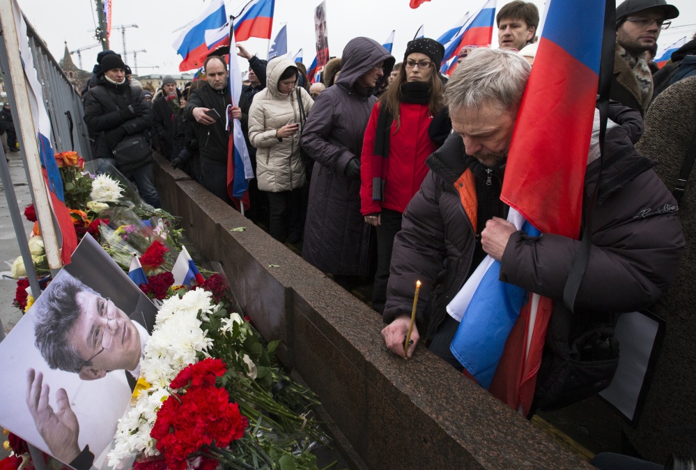 A man cradles a Russian national flag and lights a candle Sunday at the place where Boris Nemtsov, a charismatic Russian opposition leader and sharp critic of President Vladimir Putin, was gunned down on Friday near the Kremlin, in Moscow.