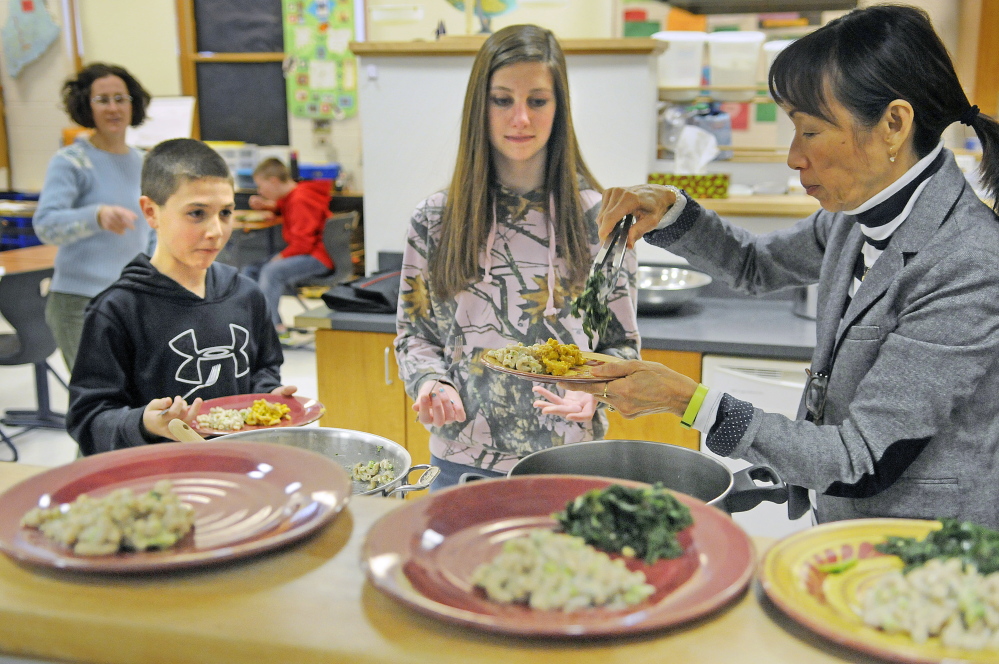 Alyssa Wingate, right, serves a meal she volunteered to help Cony High students Liz Young and Benjamin Lucarelli prepare after classes at the Augusta school. The students learn how to make healthy meals as part of the Food Matters program.
