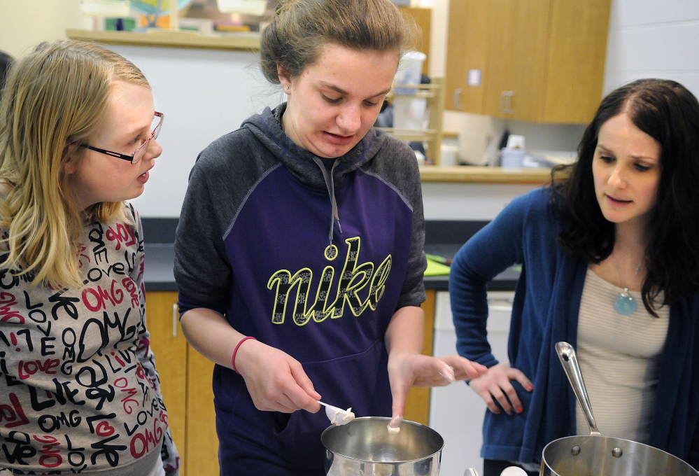 Dietitian Jacqueline Stevens, right, helps Cony High students Megan Greaton, center, and Camryn Elliott measure several tablespoons of butter while cooking a meal after classes at the Augusta school. Stevens is teaching the students how to prepare healthy meals as part of the Food Matters program.