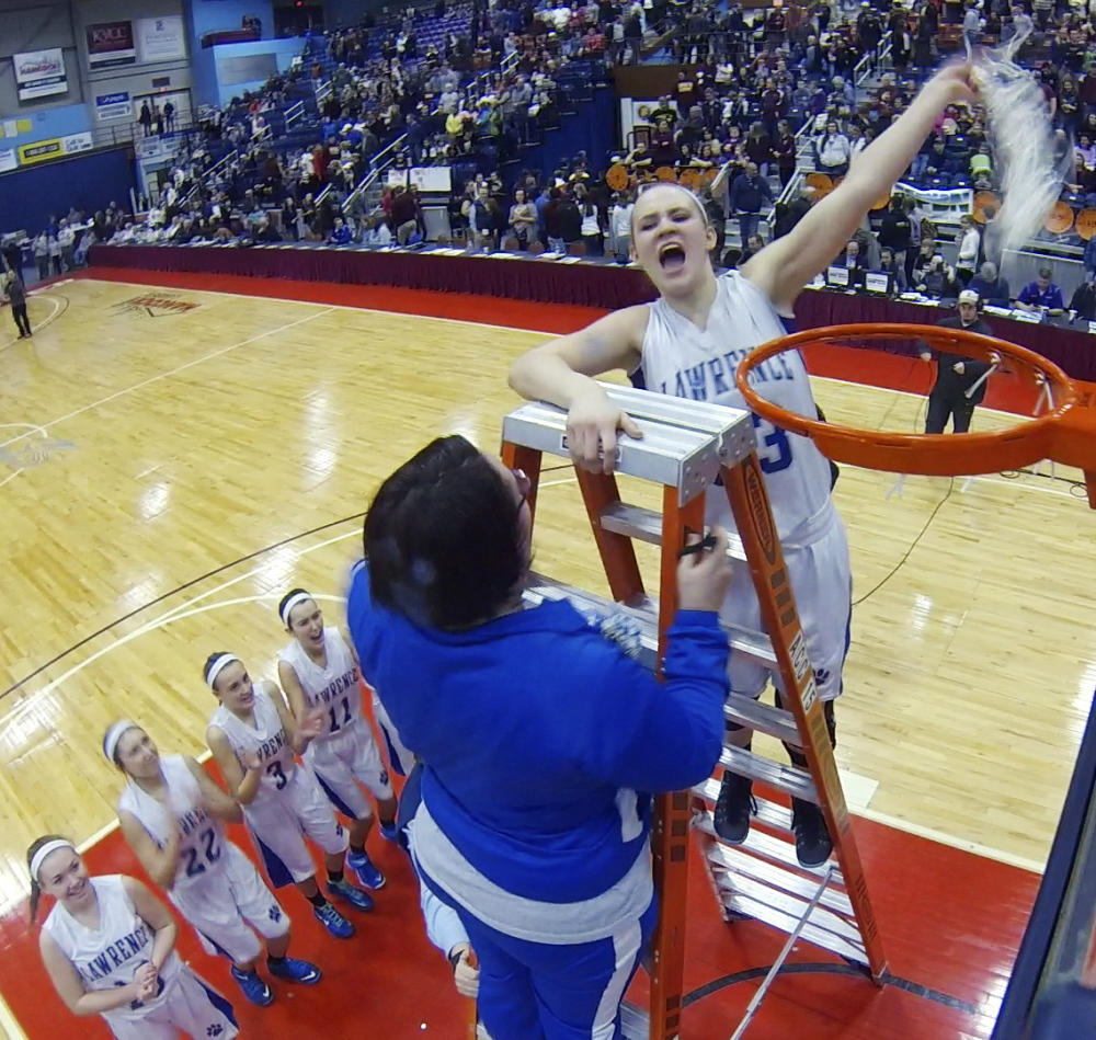 Lawrence manager Kellie Goldsmith, left, and center Nia Irving celebrate on top of the ladder after cutting down a net after the Bullodogs beat Thornton Academy for the Class A state championship Saturday at the Augusta Civic Center.