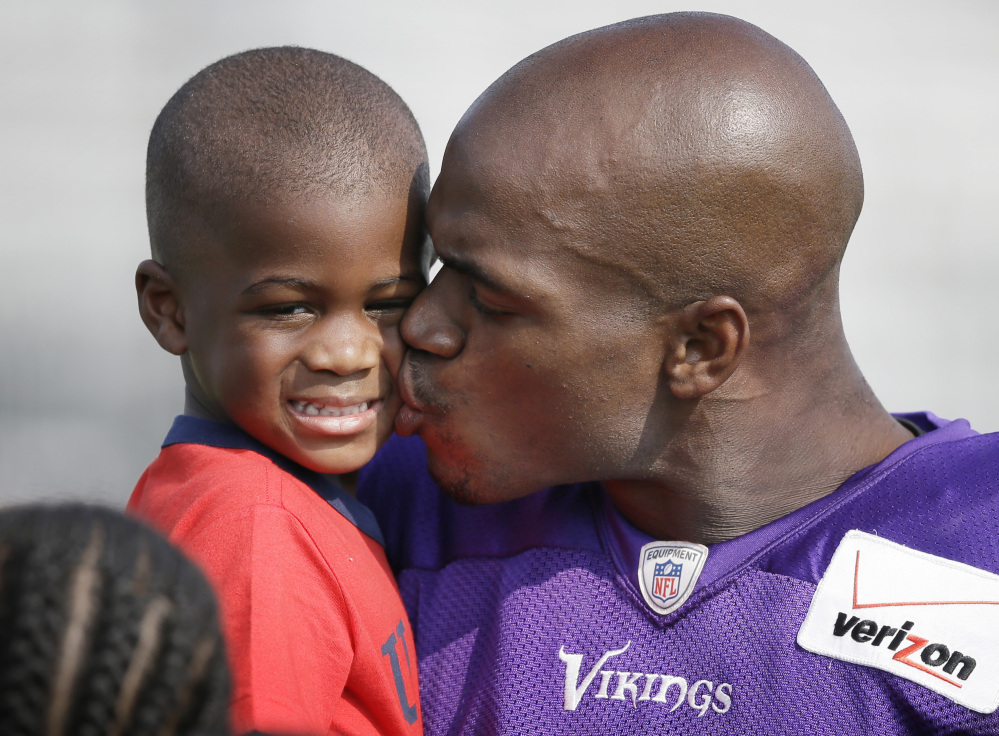 In this Aug. 2014 photo, Minnesota Vikings running back Adrian Peterson gives his son Adrian Jr. a kiss following a practice in Mankato, Minn. A federal judge has cleared the way for Peterson to be reinstated, and if the Minnesota Vikings don’t want Peterson back, a bidding war may begin on the former MVP.