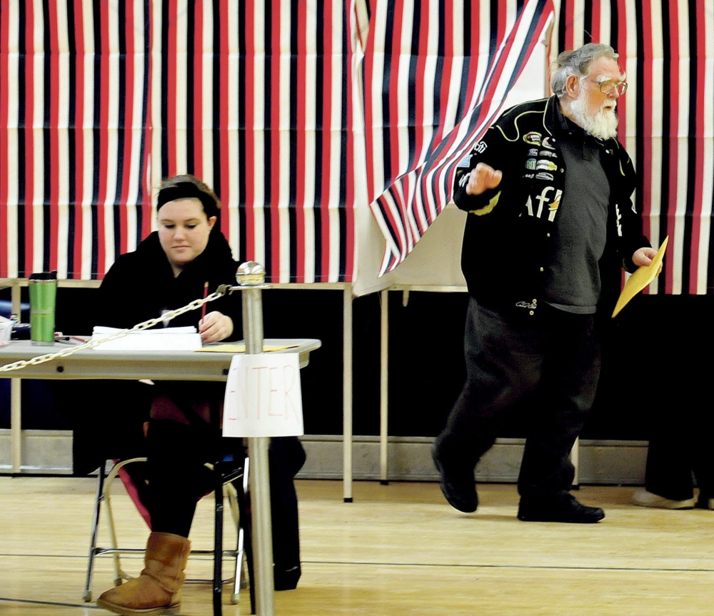 Norridgewock resident Elwin Shields steps out of a voting booth past ballot clerk Lexia Dorr during elections at the Mill Stream School before the annual Town Meeting on Monday. Dorr said that it has been unusually quiet for elections this year. Following the election, residents met to tackle a 45-article warrant that included the town budget, an ordinance to require building permits on all building alterations and a proposal for a new fire station.
