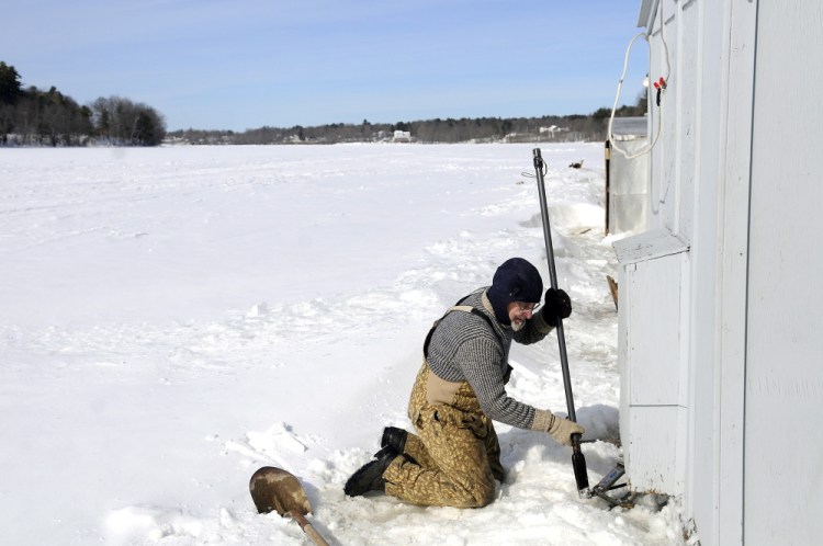 George Shaw, of Pittston, jacks his smelt camp off the Kennebec River in Pittston on Tuesday. As the river ice has built up, the persistence of freezing temperatures has kept the base of the camp below the ice surface all winter, he said. With a thaw inevitable, Shaw elevated the camp off the ice to be able to pull it ashore quickly. He estimates that more than 2 feet of ice remain on the river.