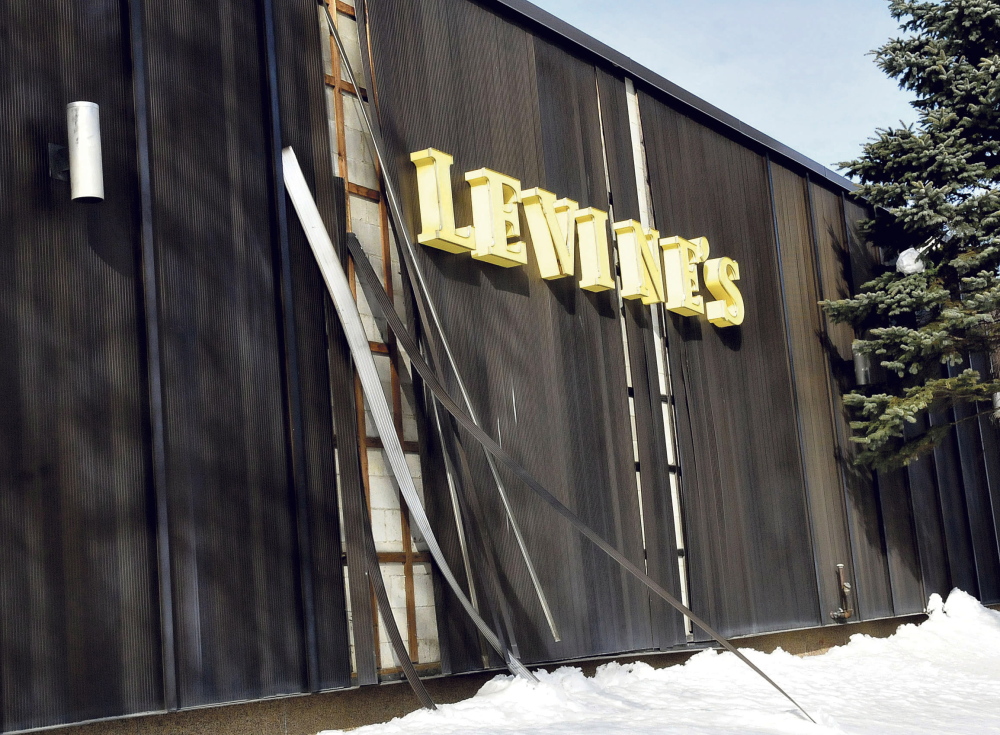Detached aluminum siding leans against the former Levine’s clothing store Tuesday in Waterville. The city’s code enforcement officer says that while the siding is not heavy, it could pose a traffic hazard if it blows into the busy intersection of Front, Main and Bridge streets.