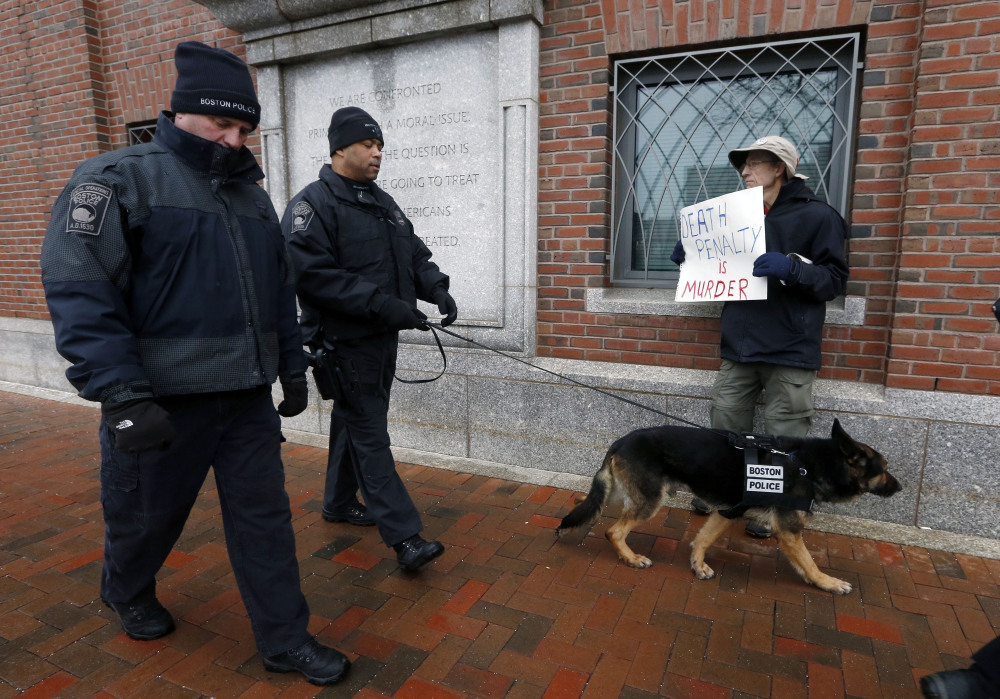 Boston police officers walk past protester Joe Kerbartas outside federal court Wednesday in Boston, on the first day of Boston Marathon bombing suspect Dzhokhar Tsarnaev’s federal death penalty trial.