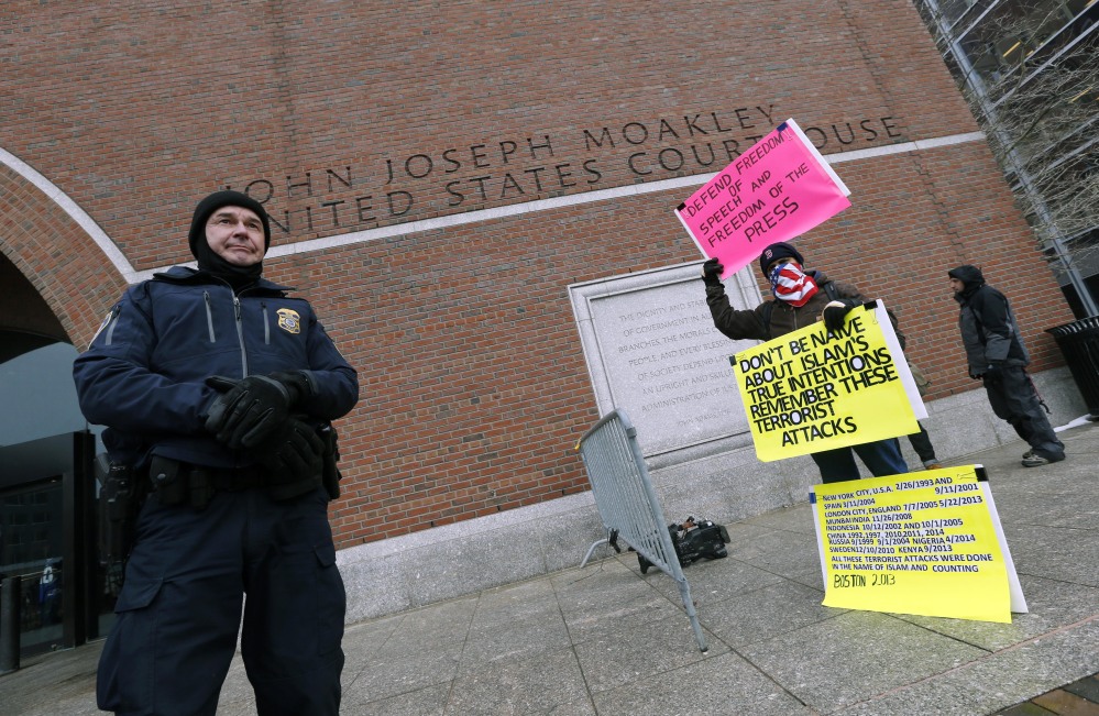 A federal police officer stands near protestor Jose Briceno, right, outside federal court, Wednesday, March 4, 2015, in Boston, on the first day of Boston Marathon Bombing suspect Dzhokhar Tsarnaev's federal death penalty trial. Tsarnaev is charged with conspiring with his brother to place two bombs near the marathon finish line in April 2013, killing three and injuring 260 people. (AP Photo/Michael Dwyer)