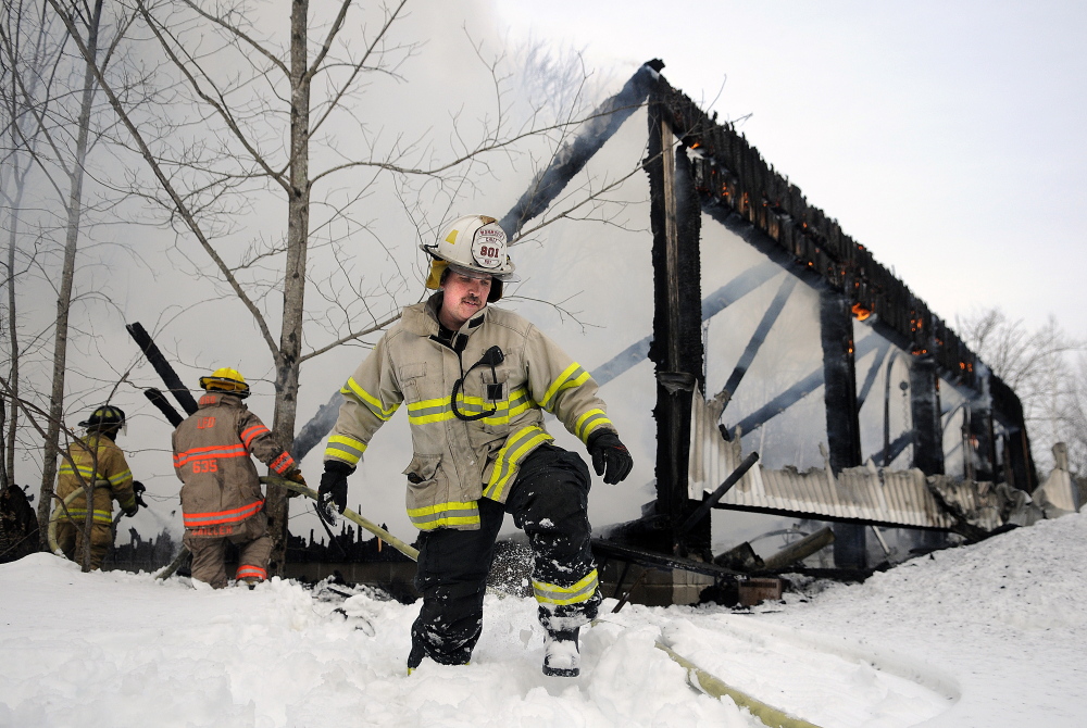 Monmouth Fire Chief Dan Roy steps through two feet of snow Wednesday after helping haul a hose to firefighters battling a blaze that destroyed a garage full of industrial equipment on Route 197 in Litchfield. 
