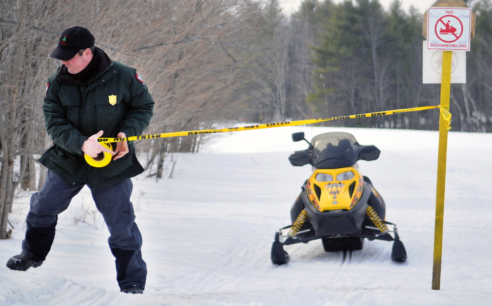 Game Warden Steve Allair closes a snowmobile trail in Readfield on Sunday after investigating complaints about riders driving off the marked trails.
