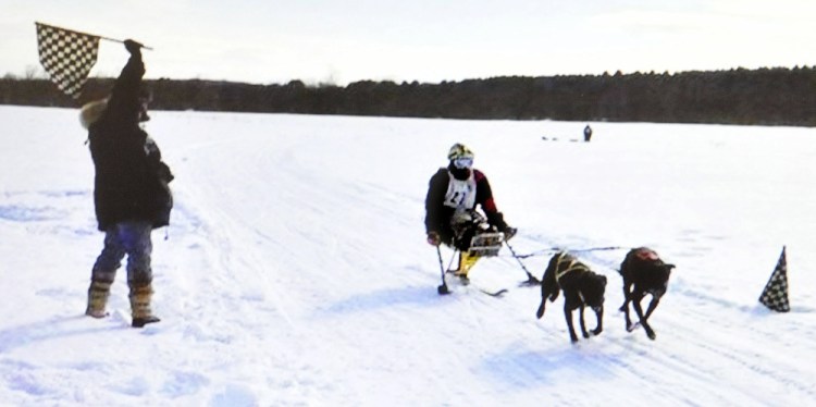 Joe Albee, of Vassalboro, crosses the finish line while skijoring with dogs in a race in Alaska. Albee passed his friend in background.