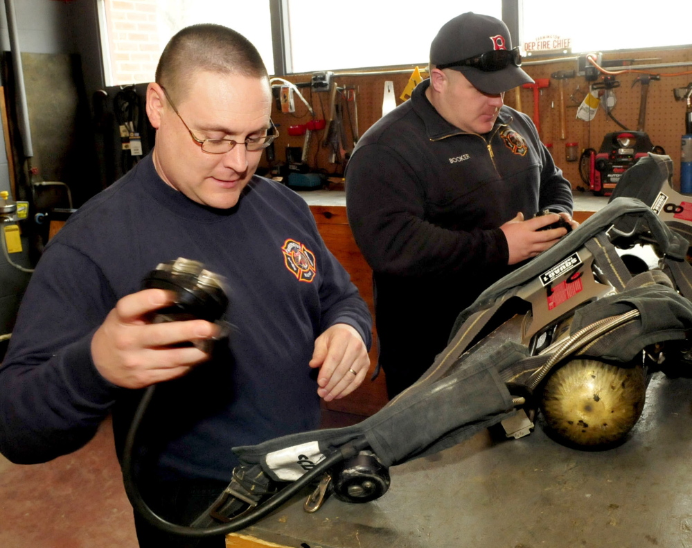 Farmington firefighters Kyle Ellis, left, and Mike Booker conduct a daily inspection of air packs recently at the Farmington Fire Department.