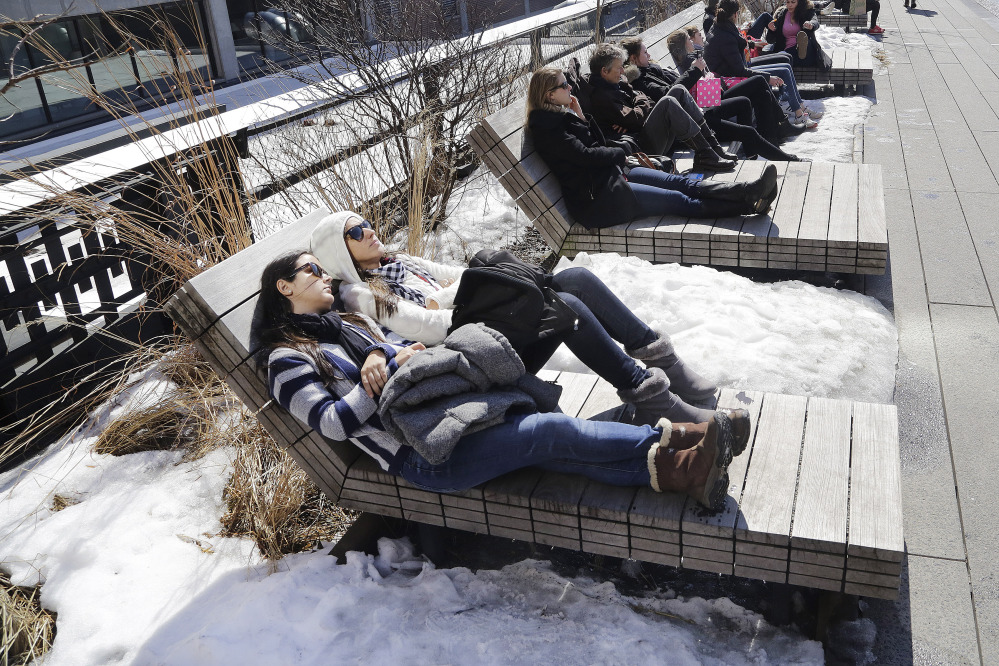 Visitors to the High Line elevated park in New York City rest on benches between piles of snow Monday, when the temperature reached 52 degrees in Manhattan, according to the National Weather Service. Cold weather is about to make a return.