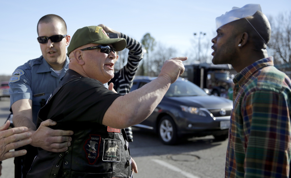 A pro-police protester, left, and counter-protester yell at each other outside the Ferguson police station Sunday in Ferguson, Mo. About 100 people came out to show their support for law enforcement.