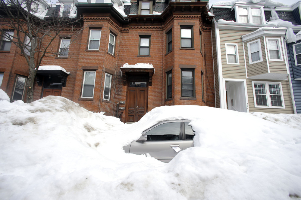In this Feb. 23, 2015 file photo, a car remains buried in snow along a residential street in South Boston. Boston’s miserable winter is now also its snowiest season going back to 1872.