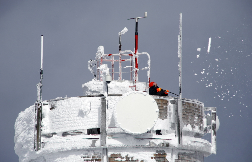 A scientist knocks rime ice off the surface of weather instruments atop the Mount Washington Observatory at the summit of the tallest peak in the Northeast.