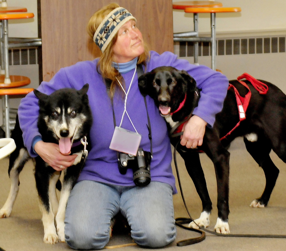 Musher Lindy Howe, of Heywood Kennel in Augusta, holds two of her sled dogs at the Cornville Regional Charter School during a demonstration on Monday.