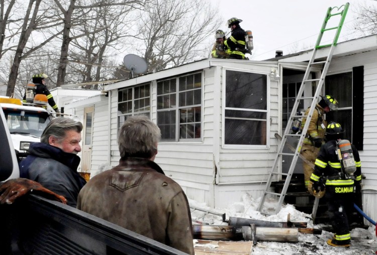 Business and homeowner Gary Bulger, left, speaks with a friend as firefighters from Winslow and Fairfield departments extinguish a stubborn fire in a home on Crummett Street in Benton on Tuesday. The address was site of another fire in which a car garage was destroyed a decade ago.
