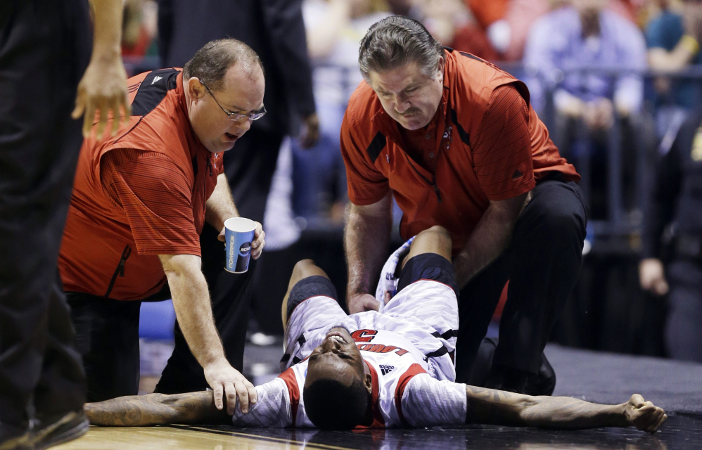 In this March 2013 file photo, trainers check on Louisville guard Kevin Ware after he injured his leg during the first half of the Midwest Regional final against Duke. The last time Kevin Ware played in the NCAA Tournament, he left the court on a stretcher, his right leg gruesomely broken in a freak incident that left his teammates in tears.  He’s looking to leave a much different impression this time around.