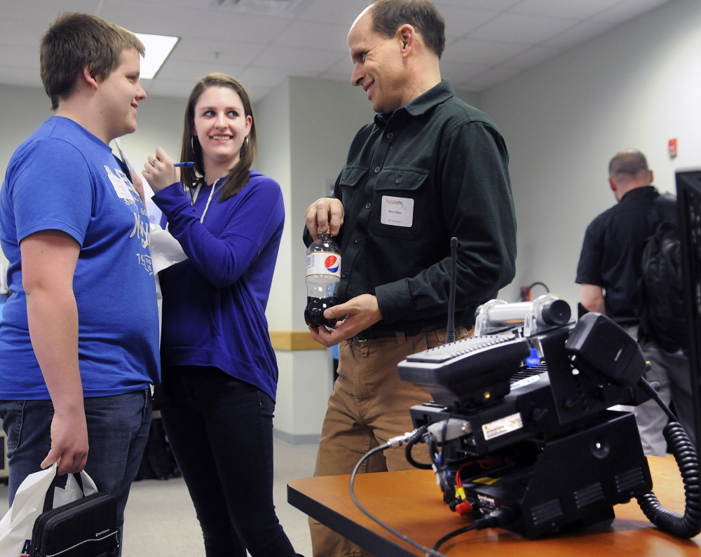 Office of Information Technology employee Marc Fisher helps Monmouth Academy students Andrew Reny, left, and Jenna Brown with questions on Thursday at the Maine Office of Information Technology’s annual Tech Night in Augusta. Fisher and his colleague, John Covert, displayed the state’s new public safety radio system to students.