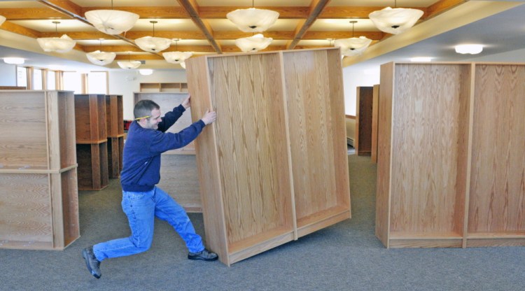 After assembling shelves, Jamie Clough, owner of JC Millwork, positions them in the new addition under construction at the C.M. Bailey Library in Winthrop on Thursday.