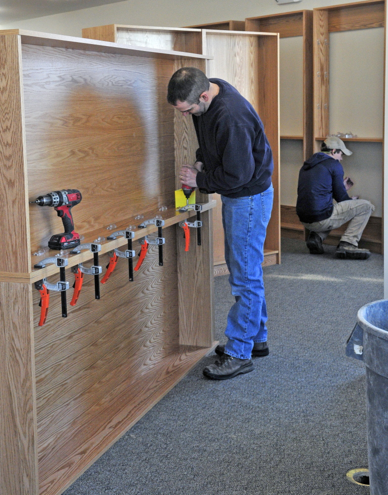 Jamie Clough, owner of JC Millwork, left, and Caleb Castonguay assemble shelves in the new addition under construction at the C.M. Bailey Library on Thursday in Winthrop.