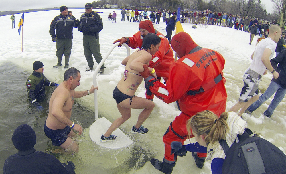 Plungers climb out of a hole in the ice after jumping into Maranacook Lake during last year’s Ice Out Plunge at the town beach in Winthrop.