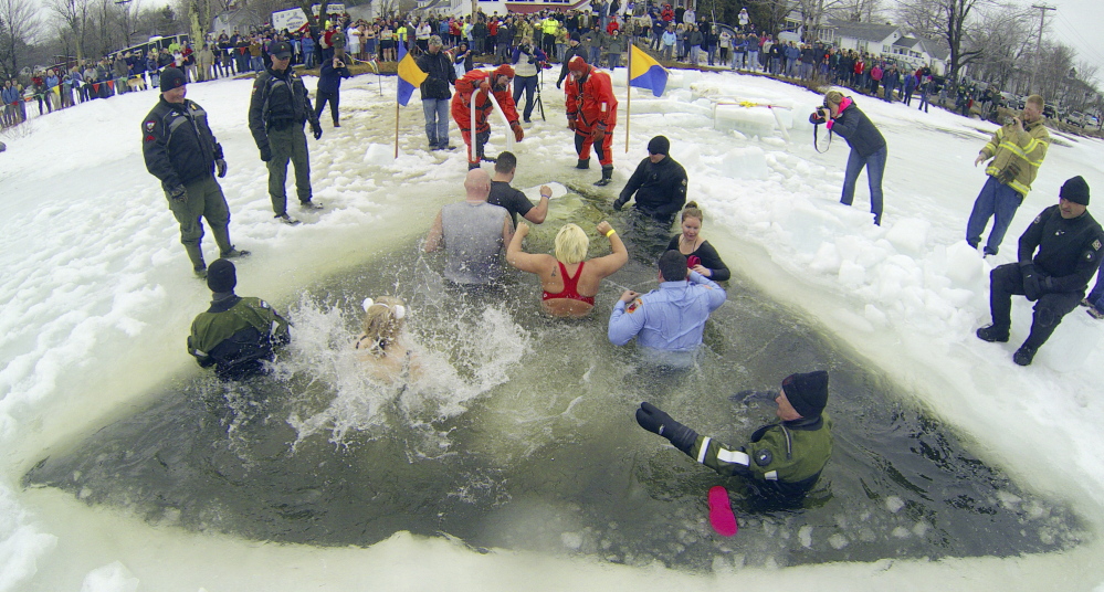 A crowd watches from shore as plungers climb out of a hole in the ice after jumping into Maranacook Lake during last year’s Ice Out Plunge at the town beach in Winthrop.