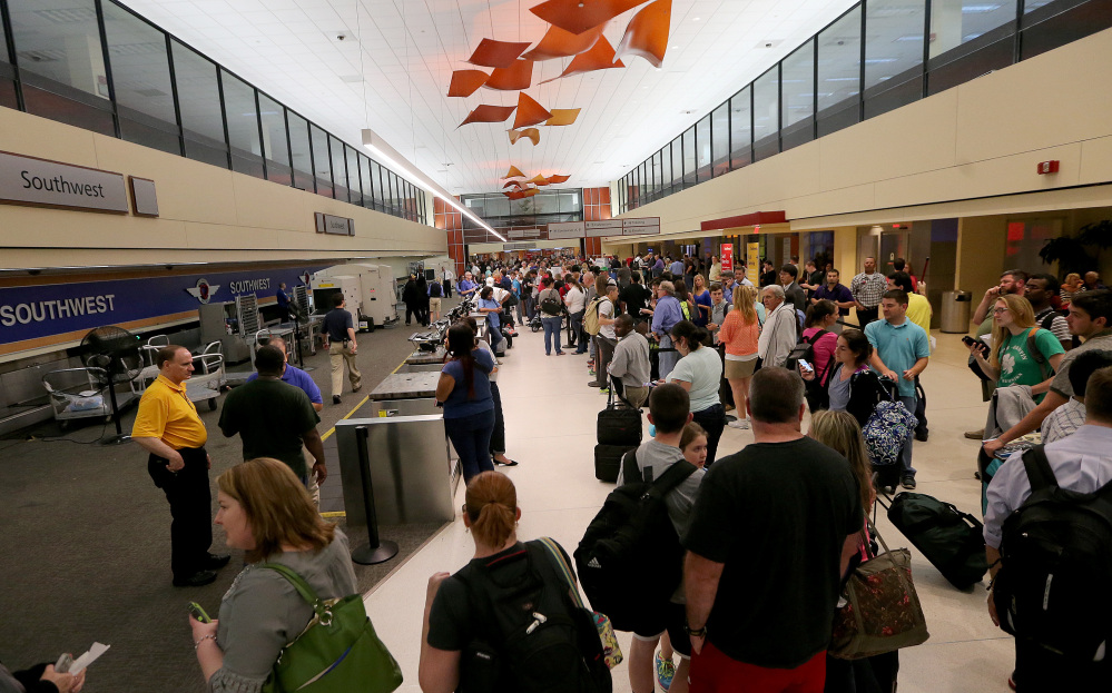 Long lines of fliers await word of their departures in the ticketing area of Louis Armstrong International Airport after a machete-wielding man was shot by a TSA employee on Concourse B on Friday.