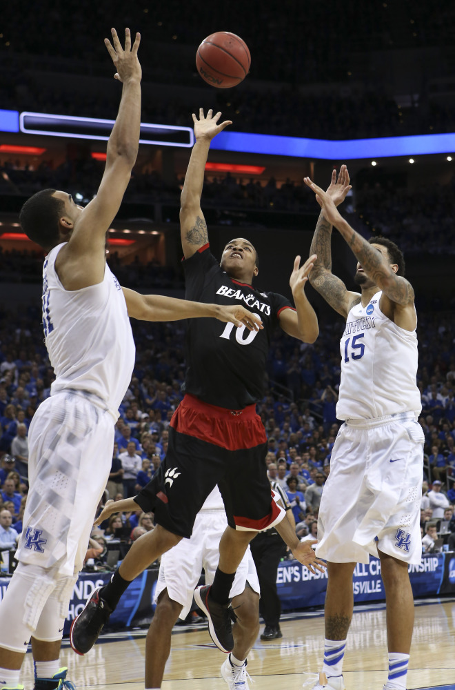 Cincinnati guard Troy Caupain shoots between Kentucky forward Trey Lyles, left, and forward Willie Cauley-Stein during the second half Saturday of an NCAA tournament game in Louisville, Ky. Kentucky won the game 64-51.