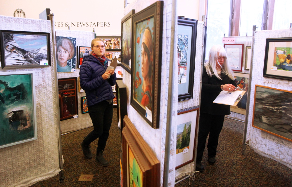 Ramey Mize, left, a Colby College Museum of Art curatorial fellow, judges pieces on Saturday for this week’s 25th annual Maine Open Juried Art Show at the Waterville Public Library. At right is fellow judge Marsha Donahue of North Light Gallery in Millinocket.