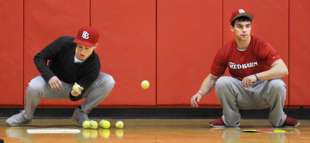 Staff photo by Andy Molloy
Cony High School baseball catchers Connor Perry, left, and Taylor Carrier snag tennis balls during practice Monday.