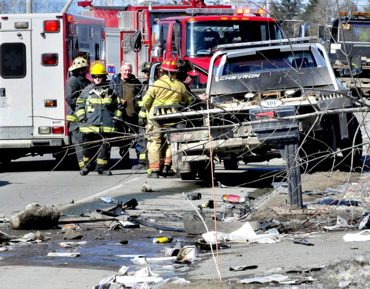 Firefighters and onlookers talk Tuesday as police reconstruct the scene of a fatal car accident on U.S. Route 201 in Madison.