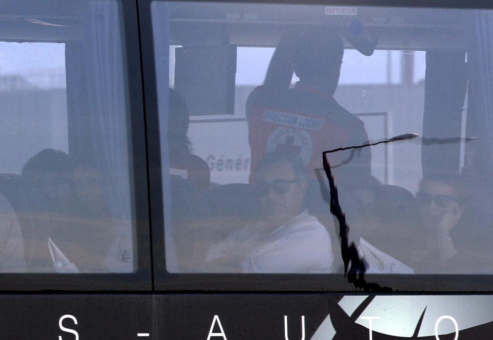 A man wearing a Red Cross jacket stands by relatives of crash victims in a bus after their arrival at Marseille airport, southern France, Thursday.