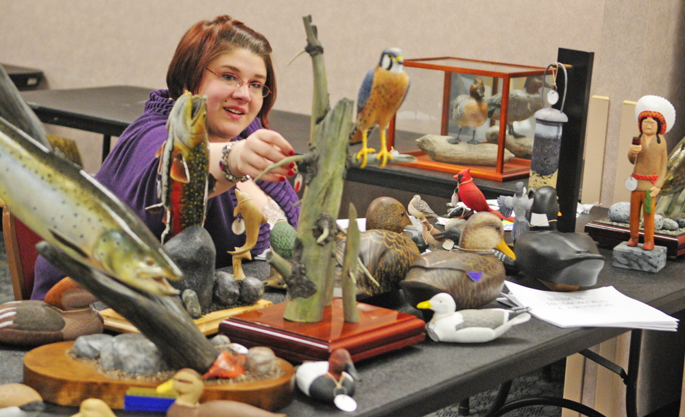 Staff photo by Joe Phelan
Manda Coulombe puts a tag on a carving as she helps set up the art and woodcarving show Thursday, the day before the opening of the Maine Sportsman’s Show at the Augusta Civic Center.