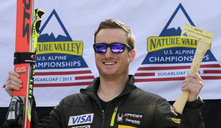 Tim Jitloff holds up his axe trophy and skis after winning the men’s giant slalom race at the U.S. Alpine Ski Championships at the Sugarloaf Mountain Friday.