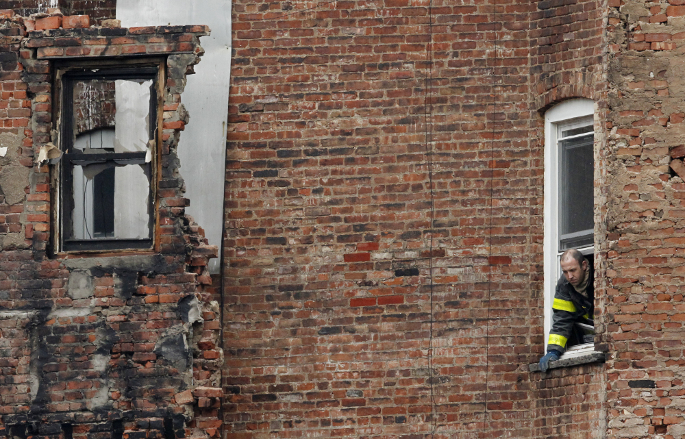 A fire official stands at the window of a building adjacent to the site of a building collapse in the East Village neighborhood of New York.