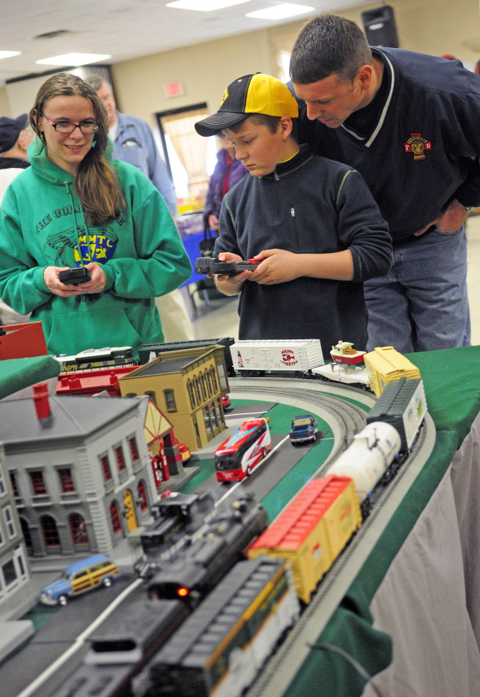 Mary Wunderlich, of Oakland, left, and Jackson Small, of Cumberland, use handheld remotes to control trains during the Maine3Railers model railroad show on Saturday at the Elks Club in Augusta. Small’s father, Dan, watches at right.