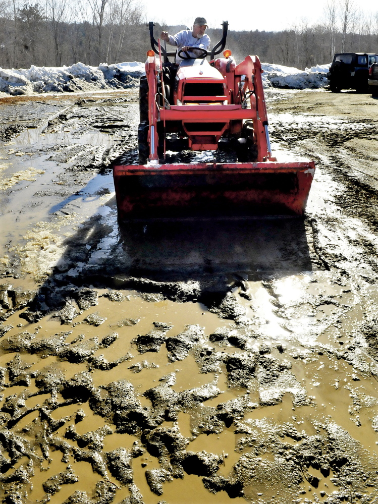Jim Boivin uses the bucket of his tractor to smooth the ruts out of a muddy portion of a parking lot at Tracy’s Kountry Kitchen on Wednesday, a new restaurant that opened Thursday.