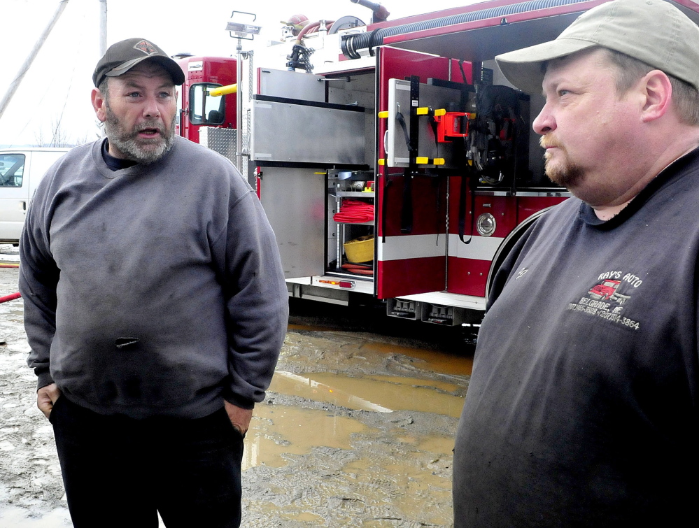 Ray Frappier, left, owner of Ray’s Garage business and property owner Percy French speak as firefighters extinguish the fire that destroyed the North Belgrade business on Monday.