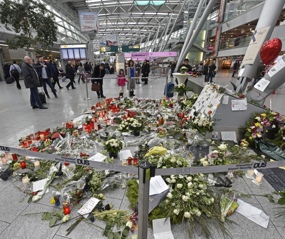 Passengers watch candles and flowers for the victims of the plane crash at the airport in Dusseldorf , Germany, Tuesday.