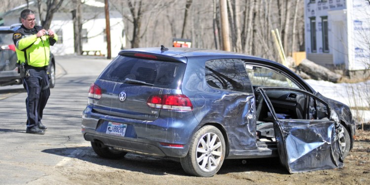 Winthrop police officer Paul Ferland photographs a wrecked car on Tuesday after it was involved in a collision with a utility pole on Winthrop Center Road, Route 135, near South Road in Winthrop. Driver Edwin Ward and passenger Sarah Ward were taken to Central Maine Medical Center in Lewiston after the crash.