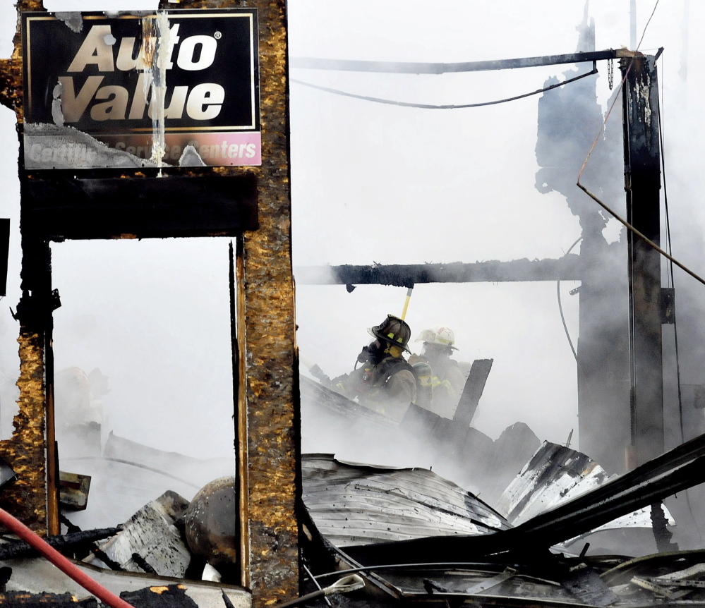 Two firefighters emerge from the smoky ruins of Ray’s Auto garage in North Belgrade that was destroyed by fire on Monday.