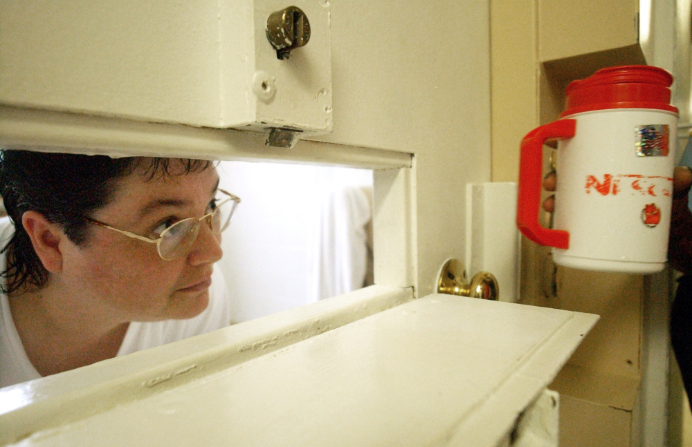 Kelly Gissendaner, the only woman on Georgia’s death row, peers through the slot in her cell door as a guard brings her a cup of ice at Metro State Prison in Atlanta.