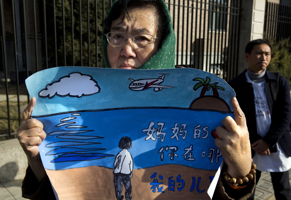 A woman whose son was on board the missing Malaysia Airlines Flight 370 holds a banner reading “Mother’s heart is broken, where are you my son” in Beijing on Sunday.