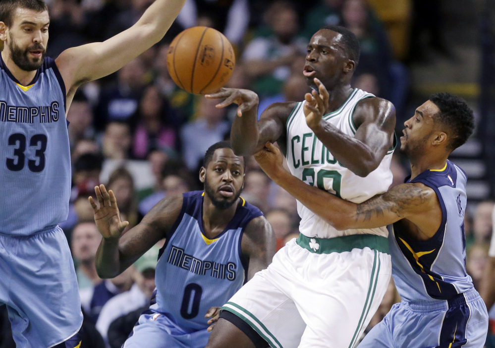 Boston Celtics forward Brandon Bass passes the ball under pressure from Memphis Grizzlies guard Courtney Lee, right, forward JaMychal Green (0) and center Marc Gasol during the first half of Wednesday night’s game in Boston. The Celtics won, 95-92, in a game that was close all the way.