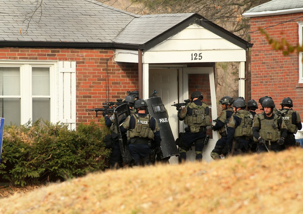 A police tactical team prepares to enter a home in the 100 block of Dade Avenue in Ferguson, Missouri, on as they search for a gunman who shot two police officers during a protest Thursday.