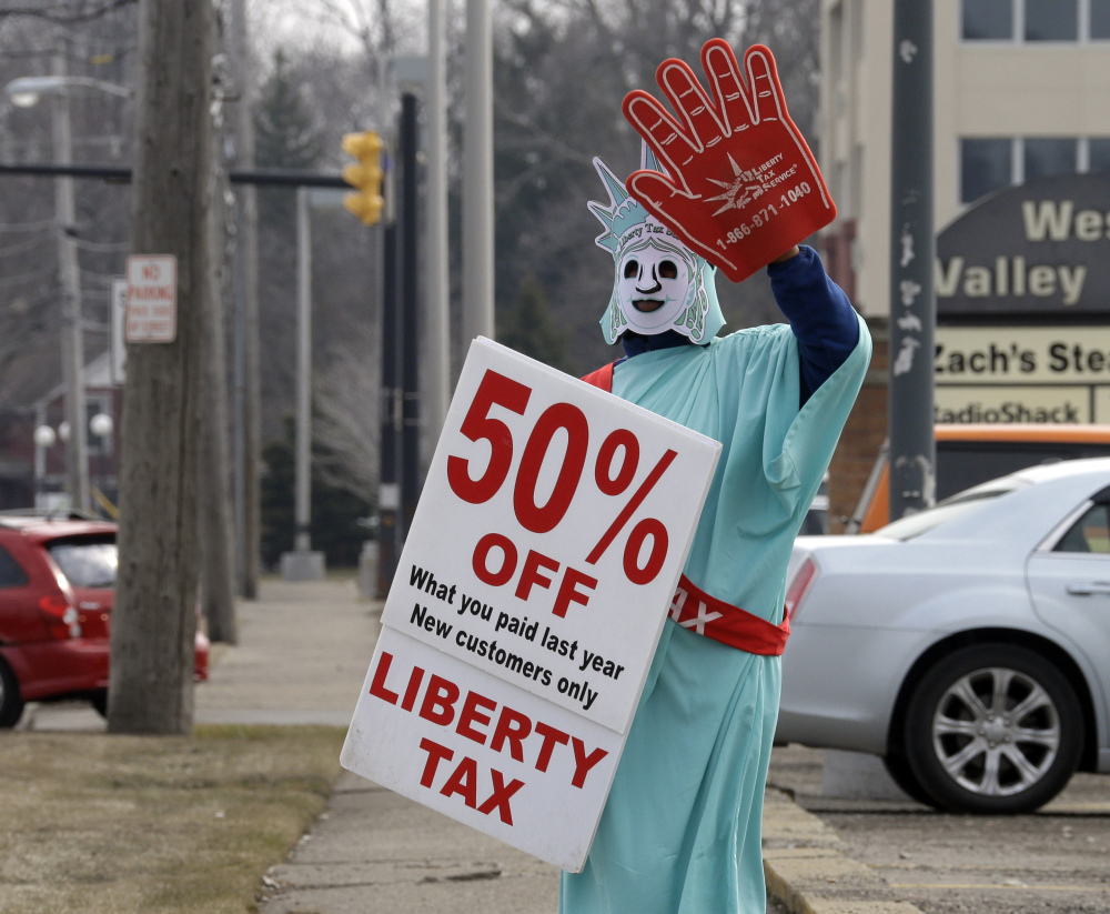 A Liberty Tax Service employee dressed as Lady Liberty waves to drivers on Saturday in Berea, Ohio. Federal regulators want tighter control of tax preparers to make sure consumers understand the fees and risks of refund advances.