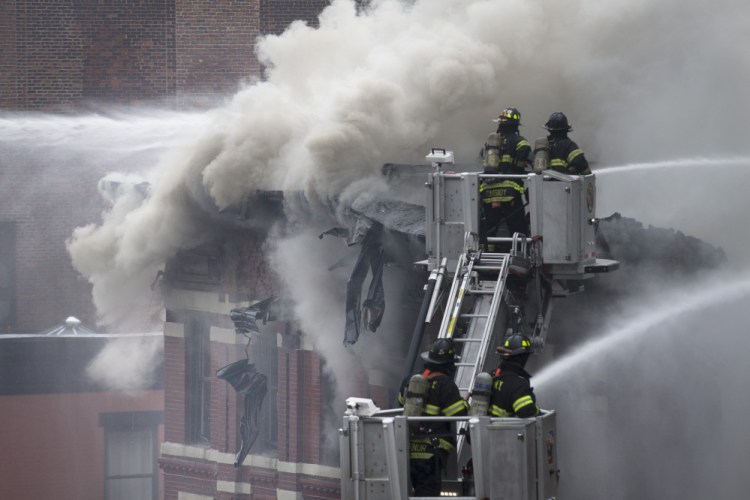 Firefighters spray water on a collapsed building in New York’s East Village on Thursday after an apparent gas explosion leveled an apartment building, partially destroyed another and launched rubble and shards of glass across streets, injuring at least a dozen people.